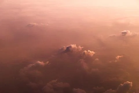 Gently pink clouds at dawn. View above the clouds from the plane. Stock Photos