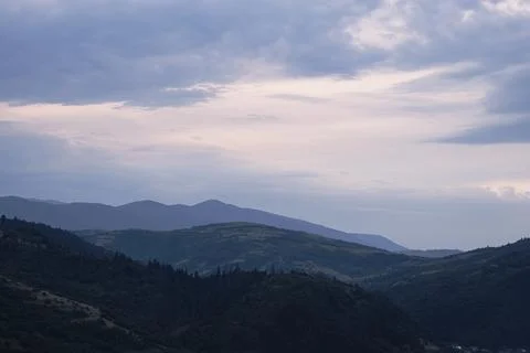 Gently pink sunset with the setting sun behind the mountains. Stock Photos
