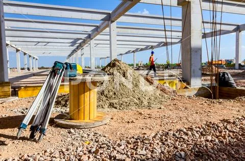 Geodesist equipment, tripod is placed next the wooden spool at building site Stock Photos