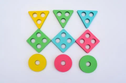 Geometric blocks lie in rows on white background. Wooden sorting toy pieces.. Stock Photos