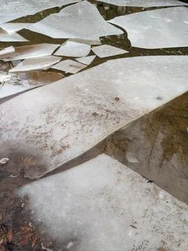 Geometric Broken Ice Chunks Floating on Shallow Brown Water Fotos Stock
