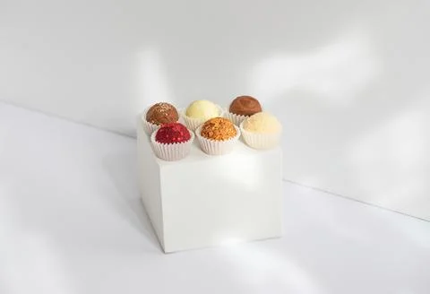 Geometric composition with candies on a white cube. Truffles on a white backg Stock Photos