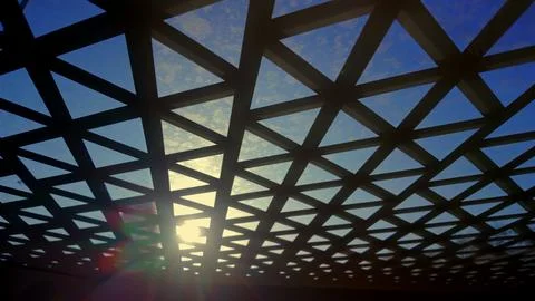 Geometric grid roof with triangular pattern against bright blue sky and sun.. Stock Photos