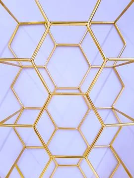 Geometric pattern of hexagons made of metal in gold color on a purple backgro Stock Photos