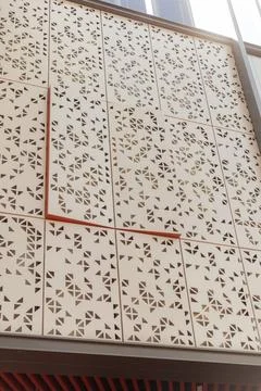 Geometric patterns cover a wall of a modern building. Sunlight shines throu.. 스톡 사진