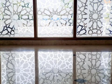 Geometric patterns reflect from the window onto the marble floor creating a.. Stock Photos