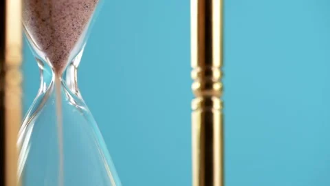 Geometric retro styled brass sand timer against a blue background Stock Footage 252519690