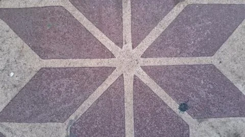 Geometric star pattern on a textured brown stone floor surface Stock Photos