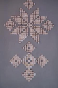 Geometric tile patterns decorating a smooth grey indoor wall surface Foto stock