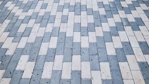 Geometric urban pavement with interlocking gray and white stones creating Stock Photos