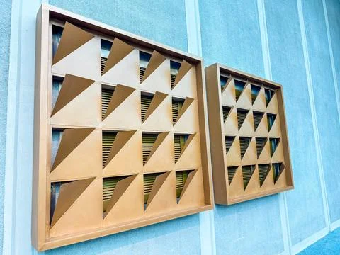 Geometric ventilation panel with triangular patterns on a blue wall. Urban de 스톡 사진