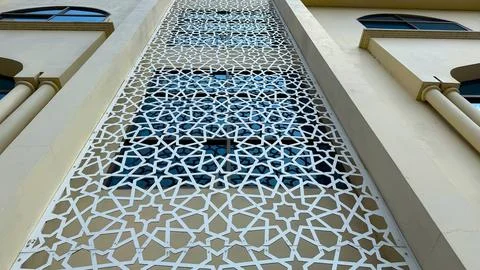 Geometric white patterned screen adorns exterior windows of a modern beige bu 库存照片