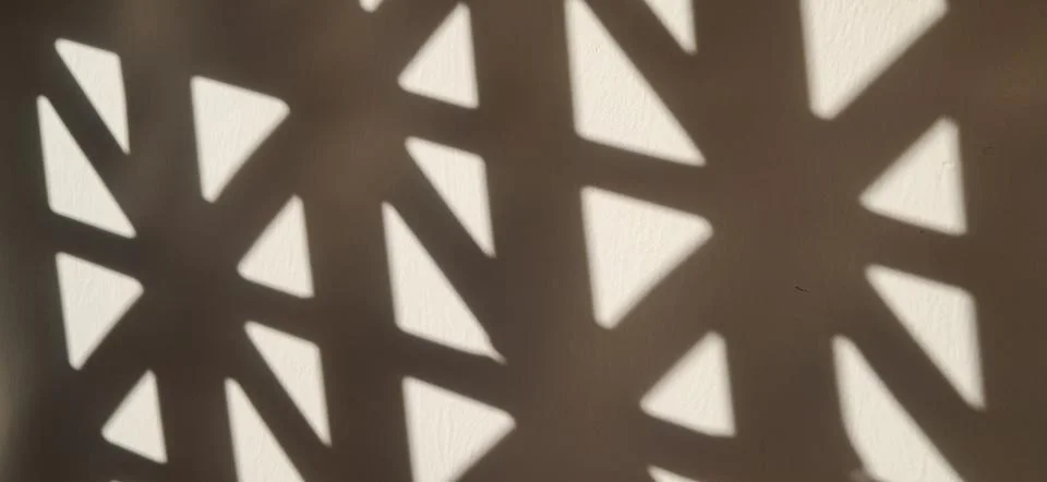 Geometric Window Shadow Pattern on Neutral Wall Stock Photos