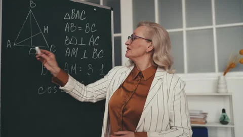 Geometry teacher in her 50s explaining material near chalkboard during lesson Stock Footage 251859466