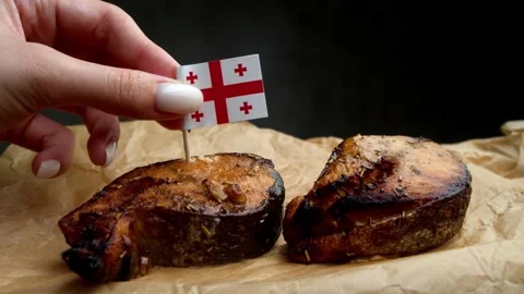 Georgian flag stuck into fish steak, symbol of Black Sea seafood for Georgian Stock Footage 323013334