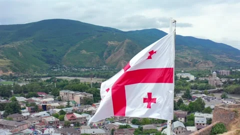 Georgian flag waves in aerial view above Gori and forested hills, supporting Stock Footage 340766677