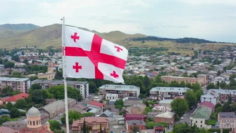 Georgian flag waves in aerial view over central Gori, historic roofs and Stock Footage 340766745
