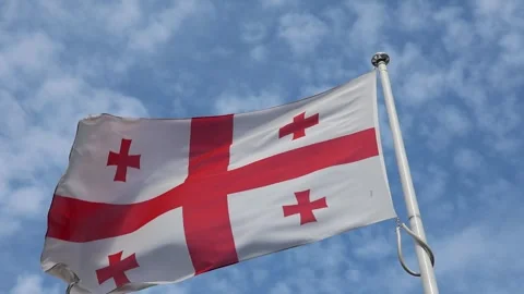 Georgian flag waving in the wind against a blue sky with clouds in slow motion Stock Footage 345758594