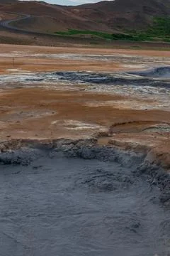 Geothermal Area with Bubbling Mud Pool and Reddish Hills in Iceland Stock Photos