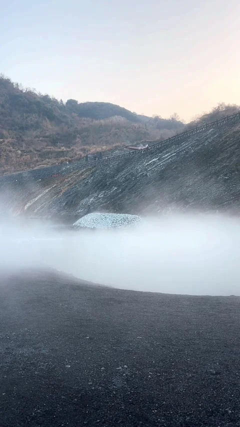 Geothermal hot spring vent emitting thick white steam from the ground on a r Stock Footage 325762794