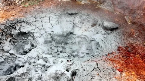 Geothermal mud pot boiling and releasing steam in a cracked mineral landscape Stock Footage 336763067