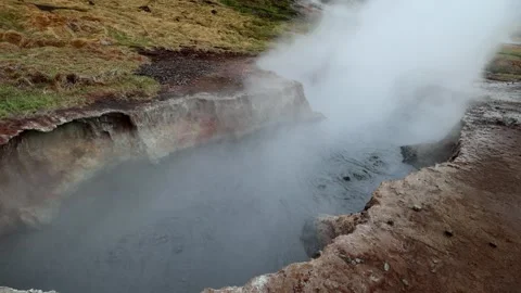 Geothermal mud pot boiling and emitting steam under overcast skies in Seltun Stock Footage 339303781