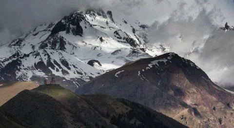 Gergeti Trinity Monastery on a background of snow-capped Caucasus Mountains a 库存照片