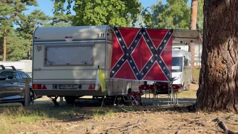 German caravan parked at a forest campsite in summer, surrounded by tall trees Stock Footage 343098181
