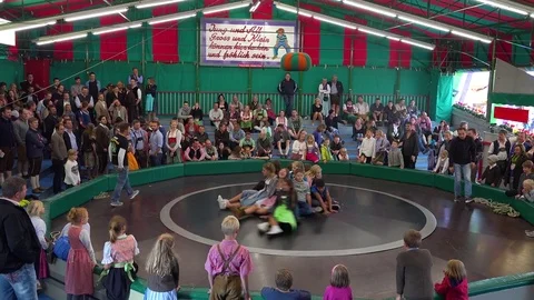 A German carnival attraction involves kids and adults spinning around on a giant Stock Footage 75685649