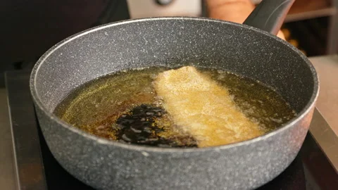 A German cook puts two ready-breaded schnitzels into hot clarified butter to Stock Footage 163048757