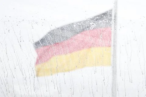 German flag on a blurred background behind glass in the rain, a sad dramati.. Stock Photos