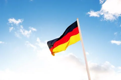 A German flag in front of clouds in blue sky Stock Photos