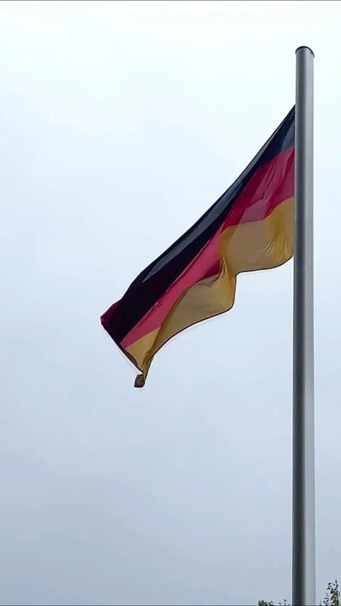 German flag waving in cloudy sky during peaceful day in city Stock Footage 329320117