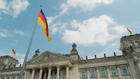 German flag waving in front of the Reichstag building in Berlin under blue sk Stock-Footage 334590881