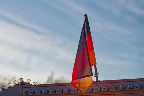 German flag waving on a pole with decorative lights against a blue sky Stock Photos