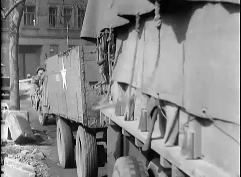 GERMANY - 1945: Canvas lorry column - Jeep passes a burned-out landmark Stock Footage 344488467