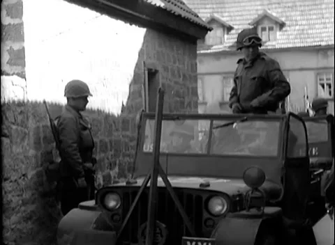 GERMANY - 1945: Command-post marker - Soldiers wait with a jeep in a walled yard 스톡 동영상 344488406