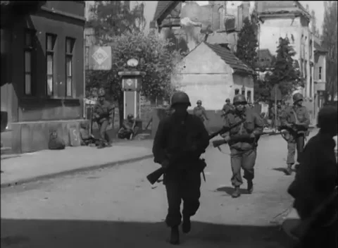 GERMANY - 1945: Coordinated patrol - Infantry advance past ARAL fuel pump 库存影片 344488694