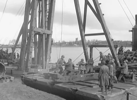 GERMANY - 1945: Deck work crew - Soldiers crowd a river barge with steel girder Stock Footage 344598331