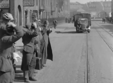 GERMANY - 1945: Escorted group - Men walk with hands raised near military truck Stock Footage 344487182