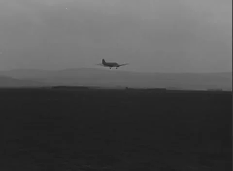 GERMANY - 1945: Hillside horizon - Gliders fly low beyond airfield wires Stock Footage 344487520