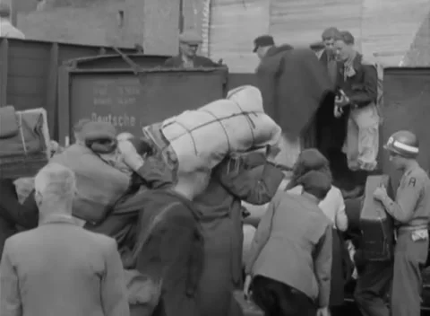 GERMANY - 1945: Repatriation train loading - Civilians lift baggage into boxcar Stock Footage 344487377