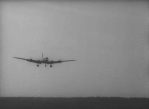 GERMANY - 1948: Final approach view - Skymaster descends toward a dark tree line 스톡 동영상 344496057