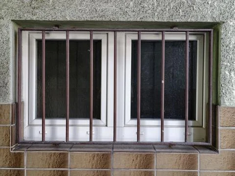 Germany 2026 Rusty barred window with metal grille in rough concrete wall w.. 库存照片
