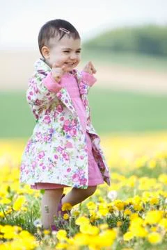 Germany, Bavaria, Baby girl walking in flower field, smiling Stock Photos