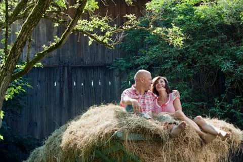 Germany, Bavaria, Couple sitting on haystack, smiling, portrait Stock Photos