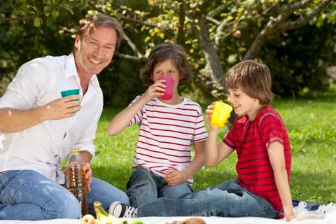 Germany, Bavaria, Father and children (8-11) having drink at picnic Stock Photos