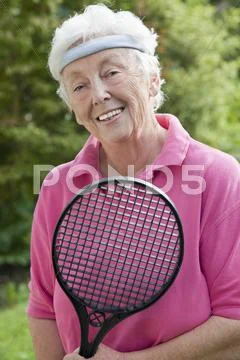 Germany, Bavaria, Huglfing, Senior woman holding badminton racket, smiling, Stock Photos