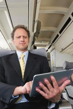 Germany, Bavaria, Munich, Businessman using ipad in business class airplane Stock Photos