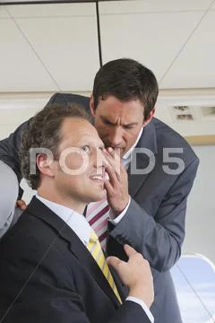 Germany, Bavaria, Munich, Businessmen whispering in business class airplane Stock Photos